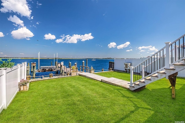 view of dock with a lawn and a water view