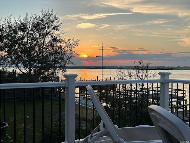 balcony at dusk featuring a water view