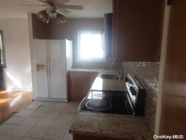 kitchen with tasteful backsplash, stainless steel range, ceiling fan, sink, and white refrigerator with ice dispenser