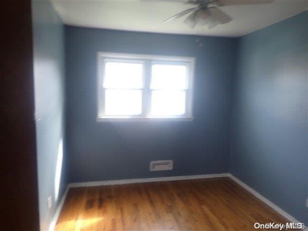 empty room with dark hardwood / wood-style floors and ceiling fan