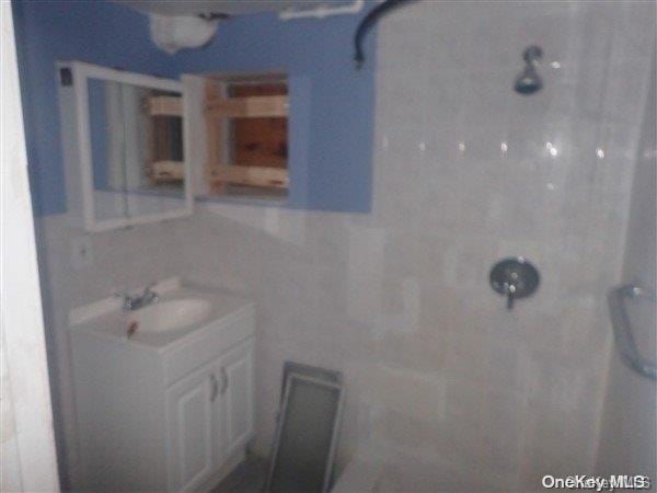 bathroom with vanity and a tile shower