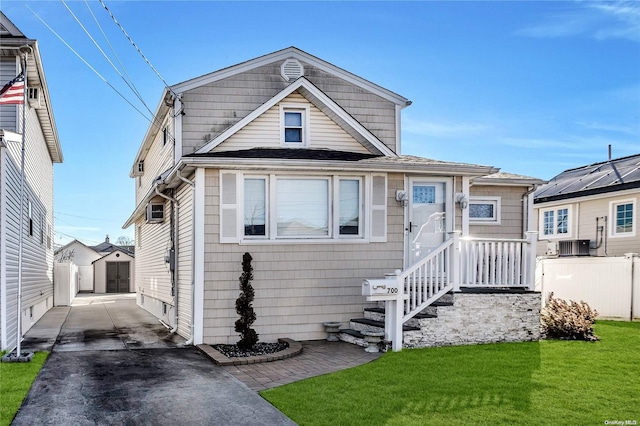 view of front of house featuring central air condition unit, an outbuilding, a front lawn, and a garage