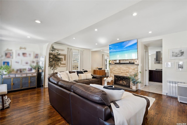 92-52 219th St, Queens Village, NY 11428 - living room featuring radiator heating unit, an AC wall unit, a fireplace, wood finished floors, and recessed lighting