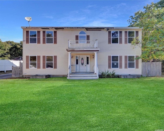 colonial inspired home featuring a balcony and a front lawn