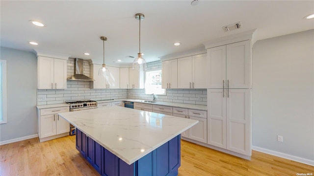 kitchen with white cabinetry, wall chimney exhaust hood, light hardwood / wood-style floors, and high end stainless steel range oven