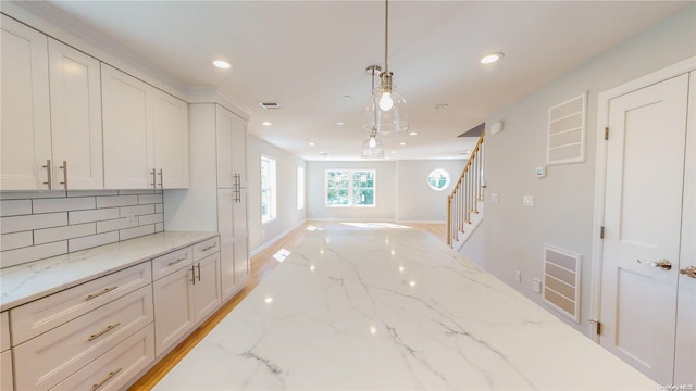 interior space featuring pendant lighting, white cabinets, and light stone countertops