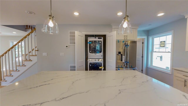 interior space with stainless steel fridge, decorative light fixtures, white cabinetry, and stacked washer / drying machine