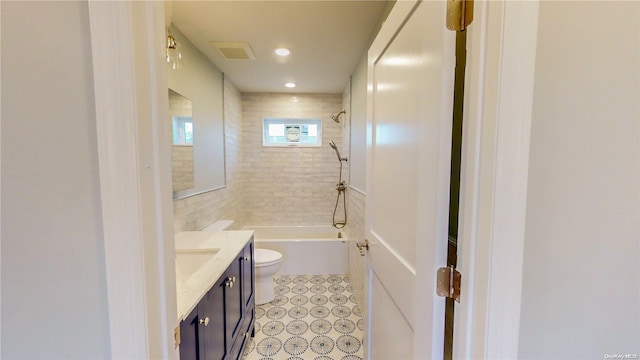 full bathroom featuring vanity, tiled shower / bath combo, and toilet