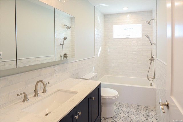 full bathroom featuring vanity, toilet, tile walls, and tiled shower / bath combo