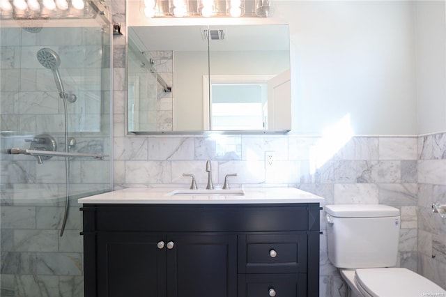 bathroom featuring a tile shower, vanity, toilet, and tile walls