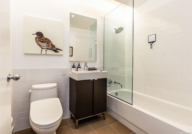 full bathroom featuring tile patterned flooring, toilet, vanity, tile walls, and tiled shower / bath