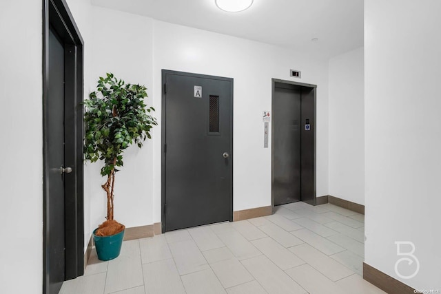 hall featuring light tile patterned floors and elevator