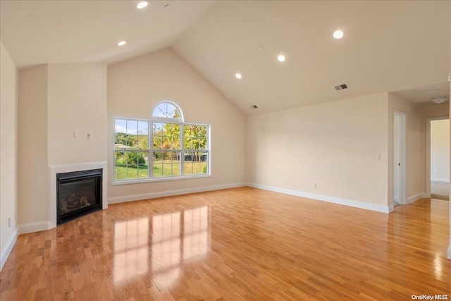 35 Steven Cir Unit 35, Dix Hills, NY 11746 - unfurnished living room featuring a glass covered fireplace, light wood-type flooring, recessed lighting, and high vaulted ceiling