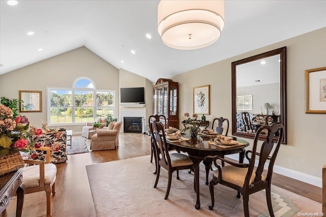 35 Steven Cir Unit 35, Dix Hills, NY 11746 - dining room featuring light wood-type flooring, a glass covered fireplace, lofted ceiling, and recessed lighting