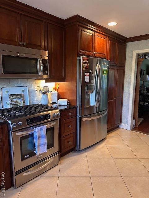 kitchen featuring light tile patterned floors, ornamental molding, and appliances with stainless steel finishes