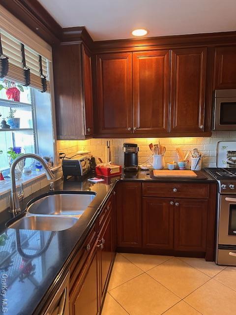 kitchen with tasteful backsplash, sink, light tile patterned flooring, and appliances with stainless steel finishes