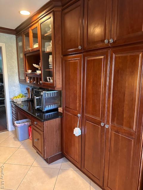 kitchen with light tile patterned floors, dark stone counters, and ornamental molding