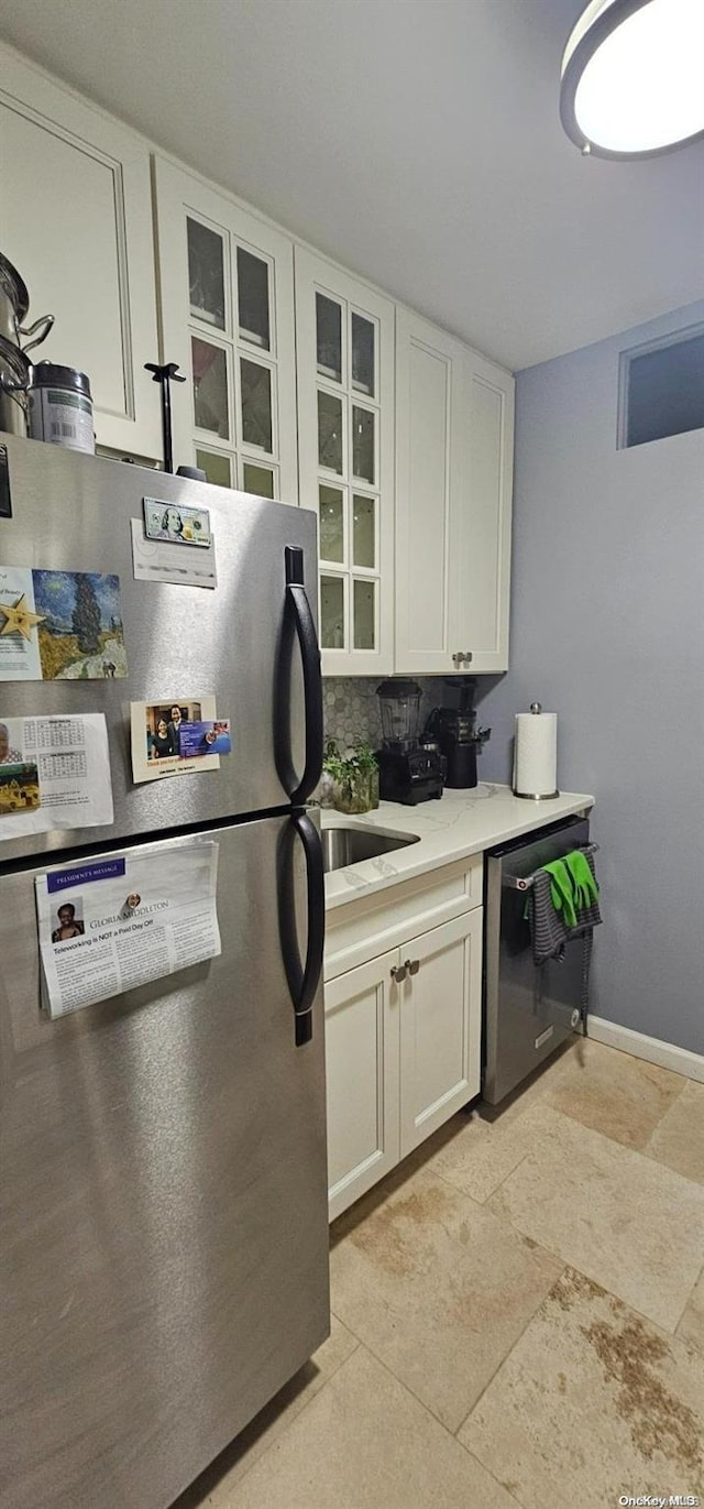 kitchen featuring decorative backsplash, appliances with stainless steel finishes, white cabinetry, and light tile patterned flooring