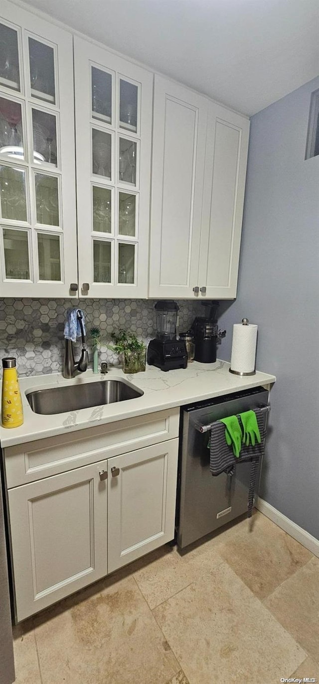 interior space featuring white cabinetry, decorative backsplash, dishwasher, and sink