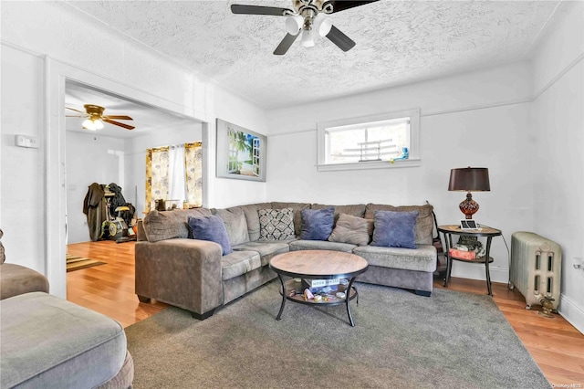 living room featuring hardwood / wood-style floors, ceiling fan, radiator heating unit, and a textured ceiling