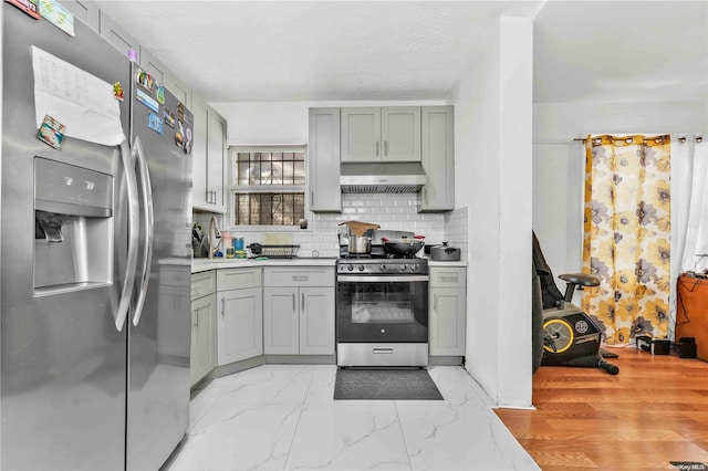 kitchen featuring decorative backsplash, appliances with stainless steel finishes, light hardwood / wood-style floors, a textured ceiling, and gray cabinets