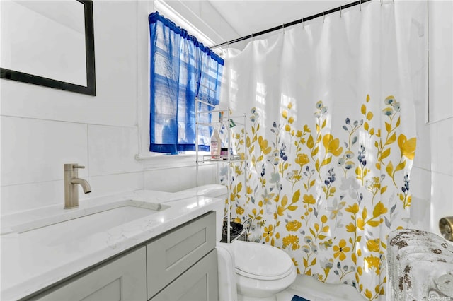 bathroom with vanity, toilet, and tile walls