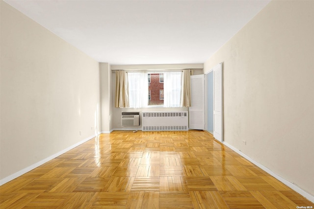 unfurnished room featuring a wall mounted air conditioner, radiator, and light parquet floors