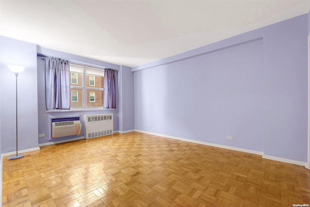 unfurnished room featuring an AC wall unit, radiator, and light parquet flooring