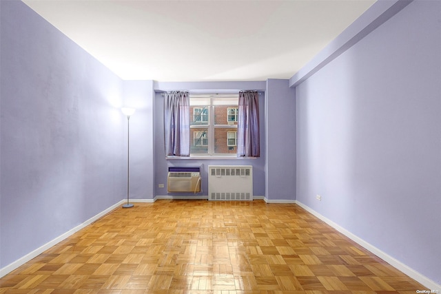 unfurnished room featuring radiator, light parquet floors, and a wall mounted AC