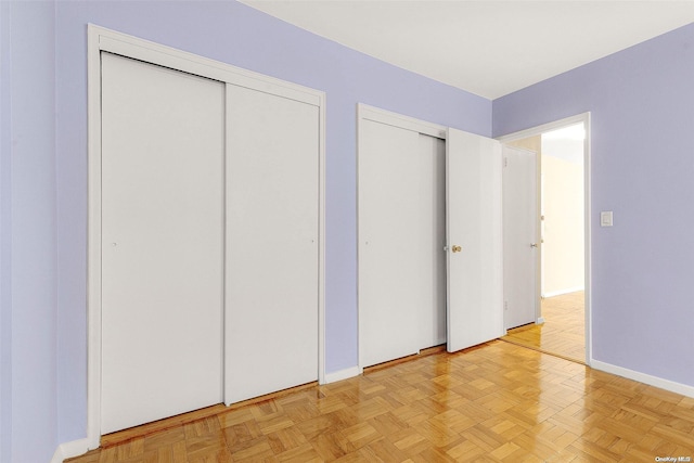 unfurnished bedroom with light parquet flooring and multiple closets