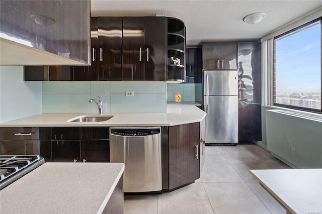 kitchen with dark brown cabinetry, sink, a textured ceiling, light tile patterned floors, and appliances with stainless steel finishes