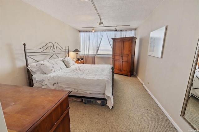 carpeted bedroom with rail lighting and a textured ceiling