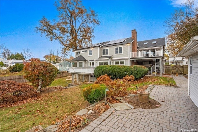 rear view of house with solar panels, a yard, and a wooden deck