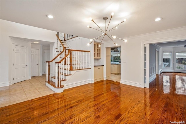 unfurnished living room featuring ornamental molding, a chandelier, and light wood-type flooring