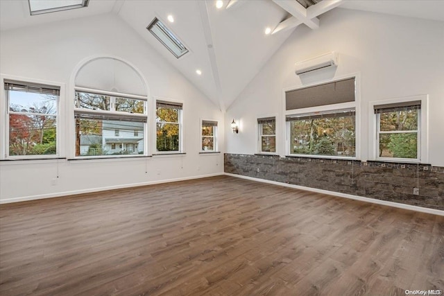 empty room with a wealth of natural light, high vaulted ceiling, and dark hardwood / wood-style floors