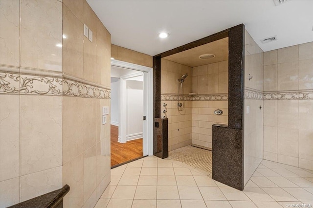 bathroom with a tile shower, tile patterned floors, and tile walls