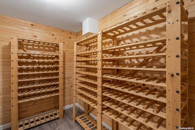 wine cellar with dark wood-type flooring and wood walls