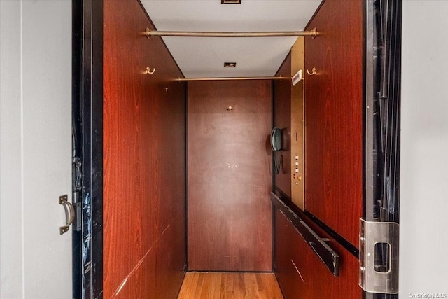 hallway with elevator and light hardwood / wood-style floors