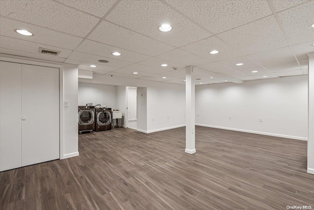 basement featuring a drop ceiling, dark wood-type flooring, and washing machine and dryer