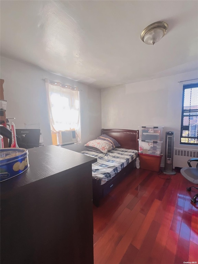 bedroom with cooling unit, dark wood-type flooring, and radiator