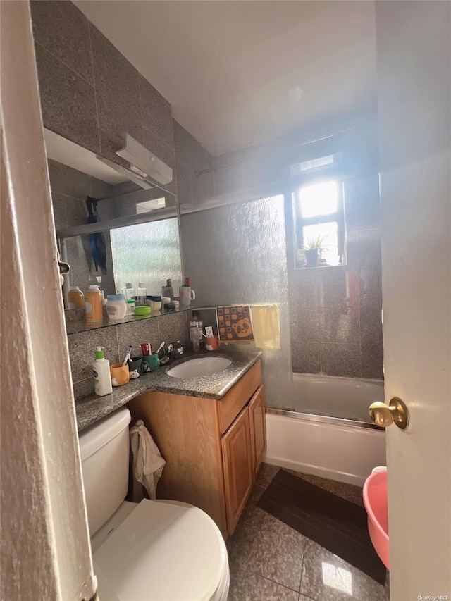 full bathroom featuring combined bath / shower with glass door, backsplash, vanity, tile patterned flooring, and toilet