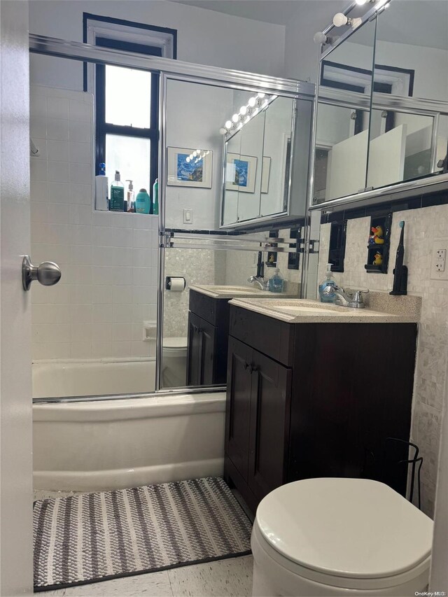 full bathroom with vanity, toilet, enclosed tub / shower combo, and tile walls