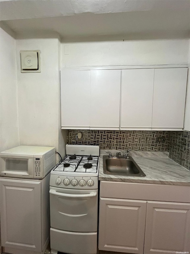 kitchen with white appliances, tasteful backsplash, white cabinetry, and sink