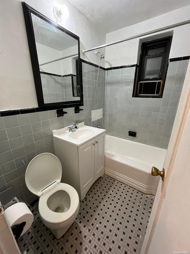 full bathroom with tiled shower / bath combo, toilet, tile walls, and vanity