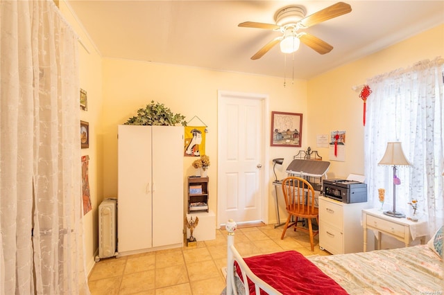 tiled bedroom with ceiling fan and radiator heating unit