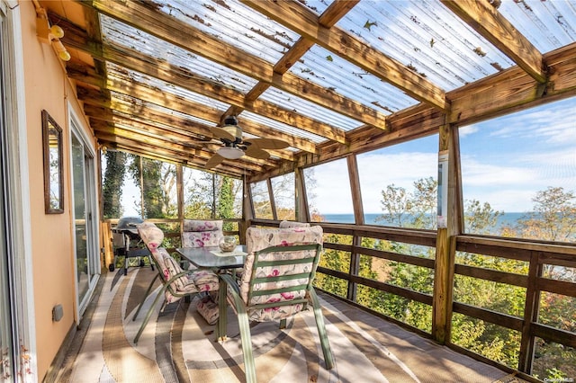 sunroom / solarium featuring vaulted ceiling with beams, a water view, and ceiling fan