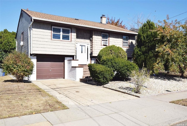 69 E 1st St, Freeport, NY 11520 - split foyer home with a chimney, concrete driveway, a garage, cooling unit, and roof with shingles