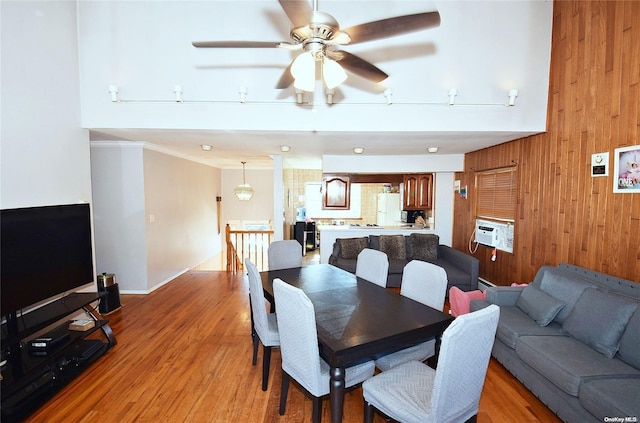 dining space featuring wooden walls, crown molding, ceiling fan, and light wood-type flooring