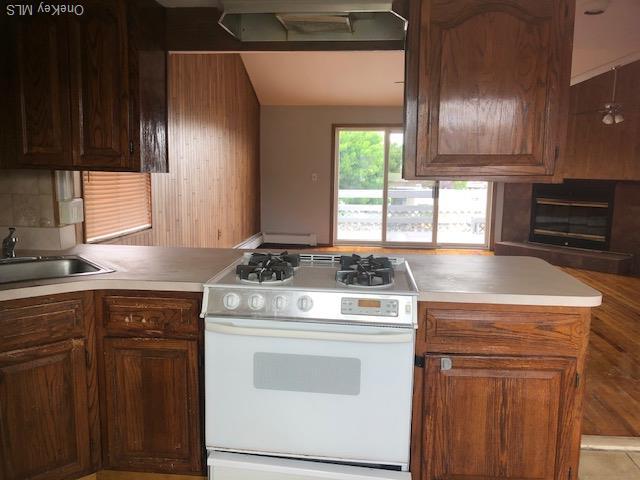 69 E 1st St, Freeport, NY 11520 - kitchen featuring white gas stove, range hood, a sink, light countertops, and a peninsula