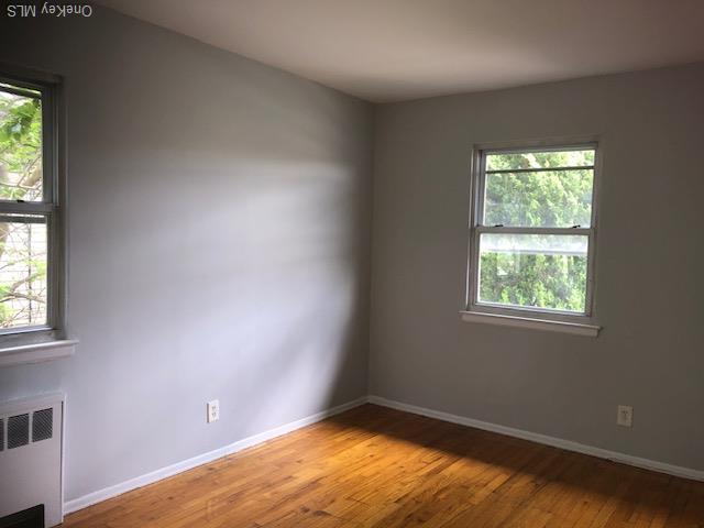 69 E 1st St, Freeport, NY 11520 - spare room with radiator heating unit, healthy amount of natural light, baseboards, and light wood-style flooring